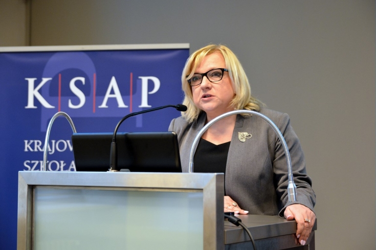Szef Kancelarii Prezesa Rady Ministrów BEata Kempa przemawia z mównicy w auli KSAP. W tle niebieski baner z logo KSAP.