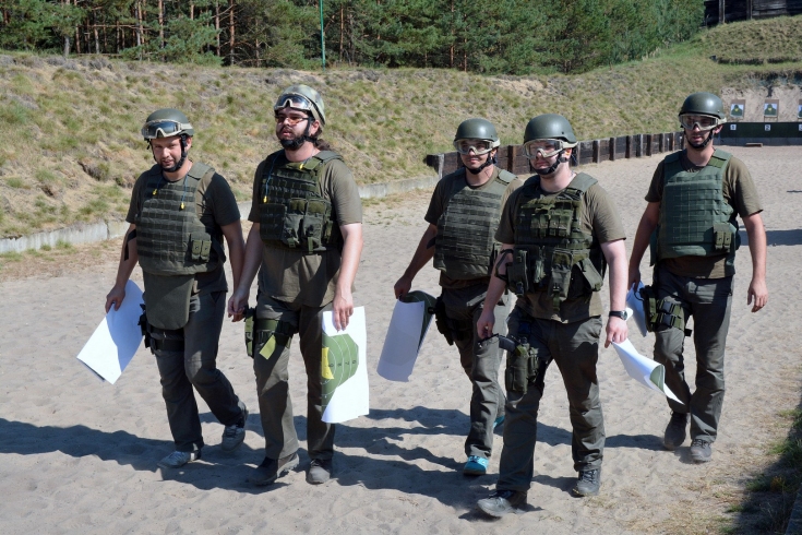 Słuchacze KSAP wracają ze strzelnicy. W rękach niosą papierowe tarcze.