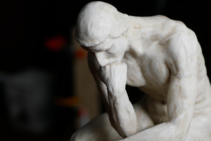 Rzeźba przestawia mężczyznę siedzącego i myślącego