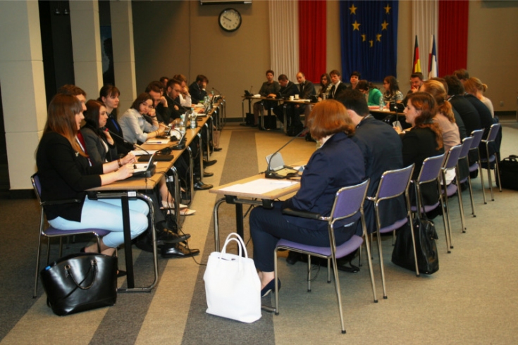 Widok na salę w której siedzą za stołami uczestnicy. Symulacja konferencji międzynarodowej.