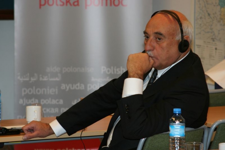 Jeden z urzędników siedzi przy ławce, ma słuchawki na uszach